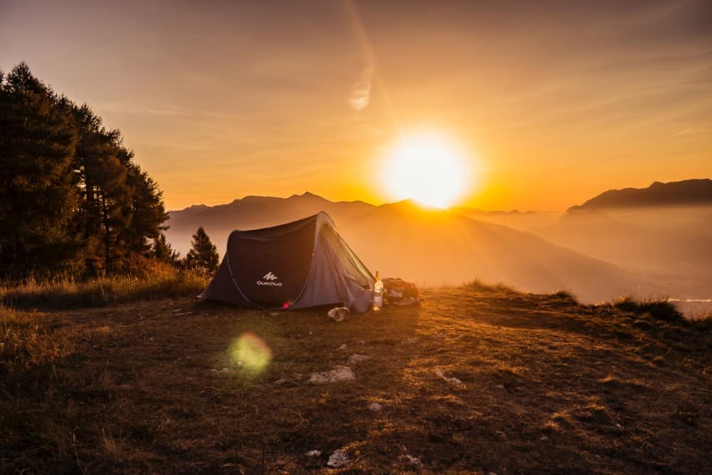 Ein Campingzelt, das bei Sonnenuntergang auf einem italienischen Berg aufgebaut wird.