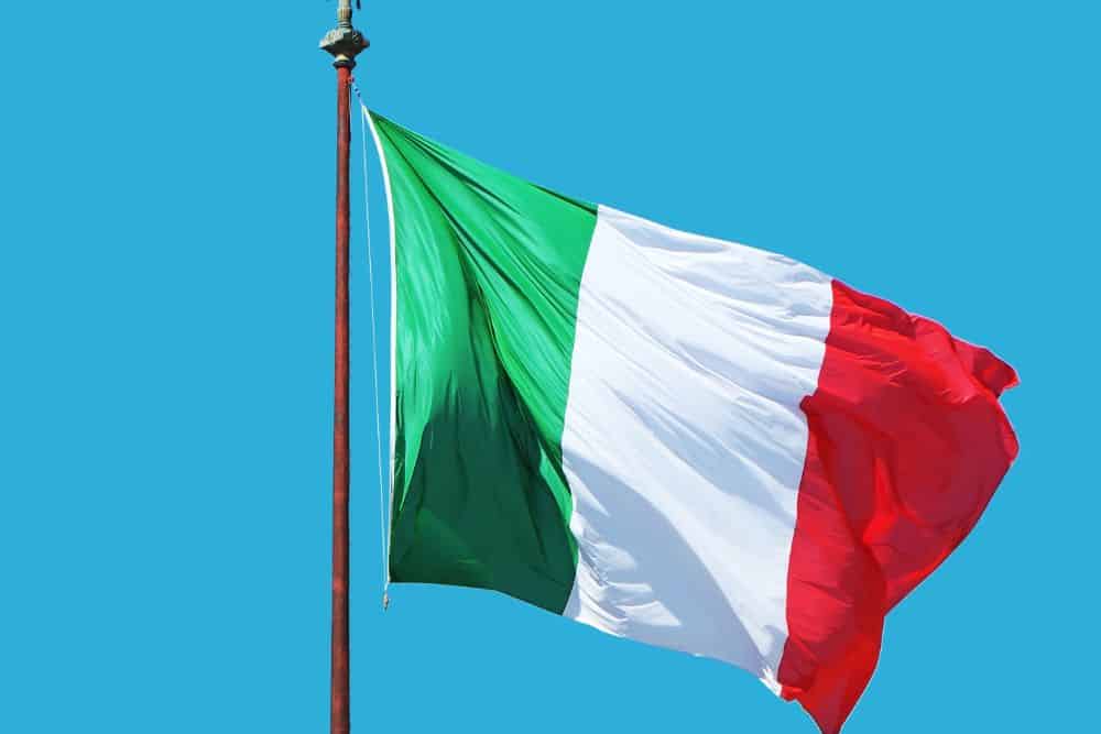 Eine italienische Flagge weht im Wind vor blauem Himmel, perfekt für Italienisch-Lern-Apps.