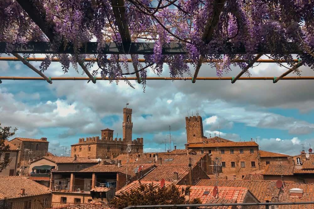 Ein Blick auf Volterra, eine Stadt mit Glyzinien auf einem Dach.